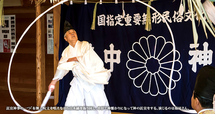 託宣神事の一つ「布舞」。呪文を唱えながら白木綿を振り回し、やがて神懸かりになって神の託宣をする。演じるのは妹尾さん。